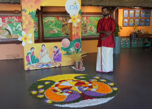 A team member posing in front of the athapookalam set by the team.