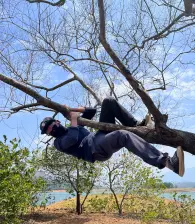 A team member enjoying himself by hanging about from a tree at Thenmala.