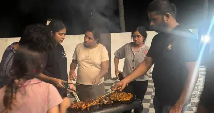 Team members engaged in conversation around the grill.