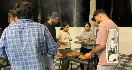 Team members engaged in conversation around the grill.