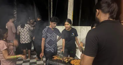 The team members huddle near the grill, enjoying the evening.